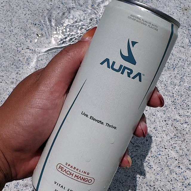 Hand holding a can of AURA